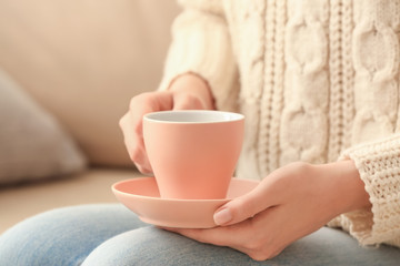 Woman with cup of tea at home, closeup