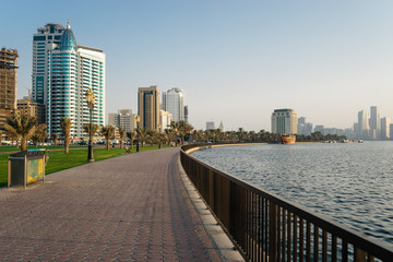 Fototapeta na wymiar A large and beautiful promenade by the sea with palm trees in the evening in the UAE | UNITED ARAB EMIRATES, SHARJAH - 17 OCTOBER 2017.