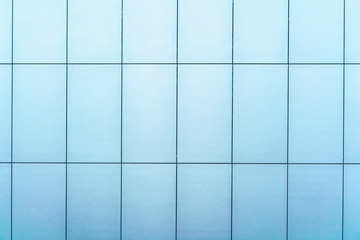stylish wall of building covered with large light blue panels on city street