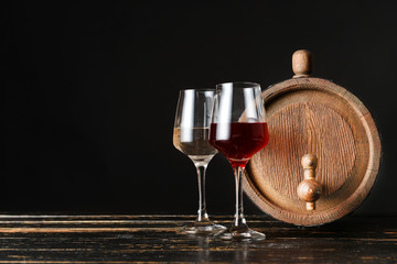 Wooden barrel and glasses of wine on dark background