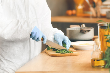 Woman in biohazard suit cooking in kitchen