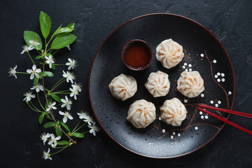 Steamed panasian dumplings with dipping sauce over black stone background, top view, horizontal shot