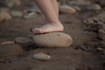 Small children's feet stand on a stone.