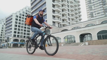 Courier with a thermobackpack rides a bicycle to the customer, the process of delivering food.