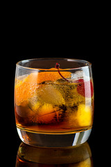 old fashion cocktail in a glass of rox on a black background