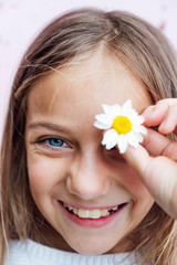 Obraz na płótnie Canvas Portrait of little girl with blue eyes and a flower