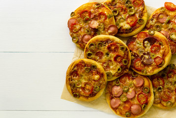 Mini pizza with sausages and tomatoes on a light background