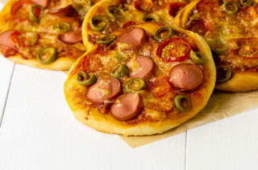 Mini pizza with sausages and tomatoes on a light background