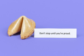 Whole fortune cookie with motivational text 'Don't stop till you're proud' on purple background