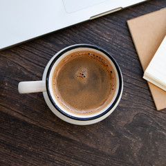 Wooden desk table with computer, notebook and hot coffee