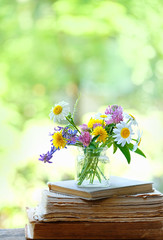 meadow flowers and old books in garden. beautiful floral composition. summer blossom season. rustic style. copy space.