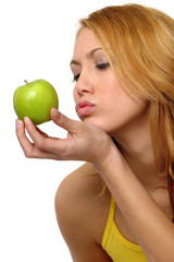 A woman trying to kiss a green apple