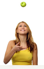 A woman throwing a green apple up in the air