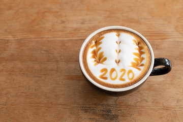 hot coffee with foam milk art 2020 on wooden table, latte art coffee