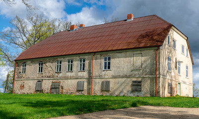 Fototapeta na wymiar landscape with a beautiful stone building, Sunday school house near Trikata church, Latvia