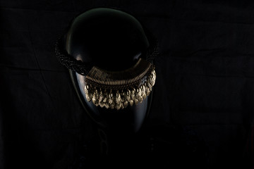 A necklace made by hand in an unusual way is presented of a portrait mannequin woman. On a dark background and highlighted at the back, the necklace glitters. Reflections. Not precious stones or metal