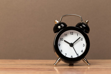 Black retro alarm clock with bells on a wooden table, daily routine concept.