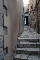 Fototapeta na wymiar Girona's landmark narrow streets with cobble stone and stairs on a long outdoor corridor and nobody on it