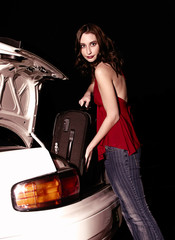 Fototapeta na wymiar A woman in jeans keeping her luggage into a car boot