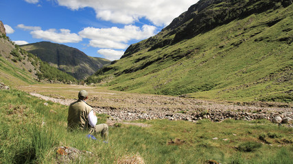 Wanderer ruht sich am Eingang eines Hochtals in schottischen Highlands aus