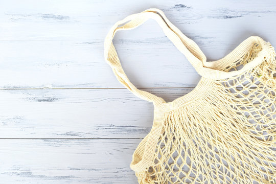 Empty beige net bag on wooden background