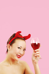 Woman with devil's horns holding a glass of red wine