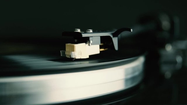 turntable plays vinyl disk on black background closeup