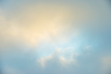 White clouds in a misty sky at a yellow foggy sunrise in an early spring morning