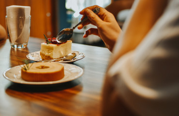 Young woman eating cheesecake strawberry, Close-up of female's hand using fork to get piece of cake.