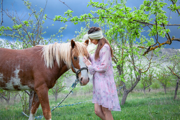 Beautiful woman dressed pink dress and fashion headdress, walking outdoor near horse paddock in the...