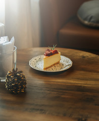 Piece of cheesecake with fresh strawberry sauce on wooden table