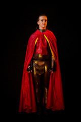 Valkyrie girl in shiny military armor and a red cloak in a dark room. Model during a photo shoot, the actress during the shooting of the film.