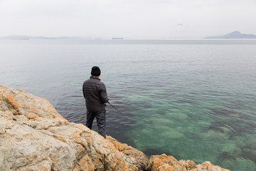 Fototapeta na wymiar Fisherman on sea fishing on the rocks