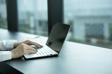 Woman hand wearing gold ring working with laptop.
