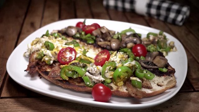 Zoom to colorful brushhetta, comfort food on wooden table.