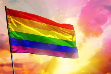 Fluttering Gay Pride flag on beautiful colorful sunset or sunrise background. Success concept.