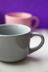 Two empty ceramic mugs of gray and pink on the table.