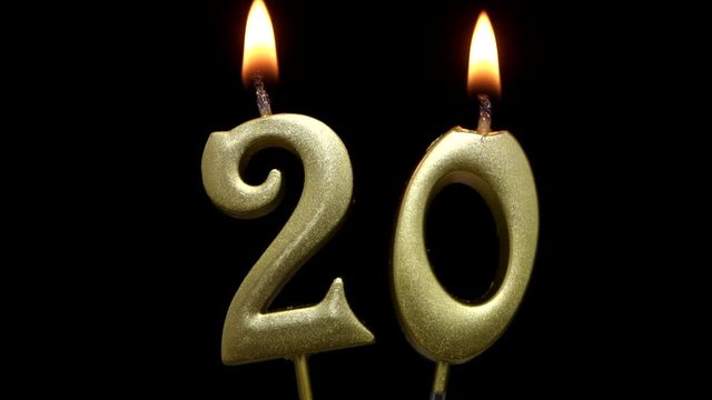 Burning golden birthday candles on black background, number 20