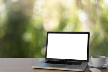 Computer laptop with white blank screen putting together with Coffee cup,on modern wooden working desk at nature bokeh background.