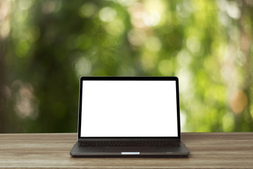 laptop on a wooden table at nature bokeh background.