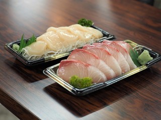 プラスチック容器に盛られた魚とホタテの刺身（北海道釧路市和商市場）