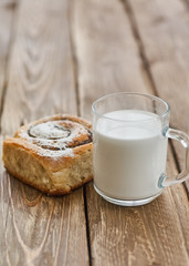 Basket of homemade buns with jam, served on old wooden table with cup of milk