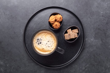 Cup of coffee, brown sugar and biscuits on stone background. Top view. Copy space