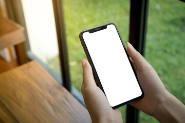 hand holding smart phone with blank screen in cafe.
