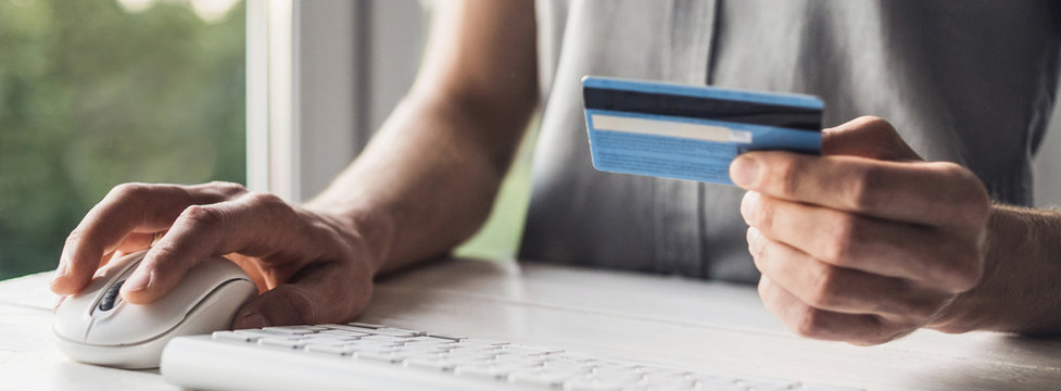 Man hand holding credit card and using laptop at home, Businessman or entrepreneur working, Online shopping, e-commerce, internet banking, spending money, working from home concept