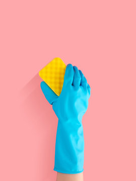 hand in blue rubber glove holding yellow cleaning sponge, cleaning and disinfection for good hygiene isolated on pink background with copy space for text or logo