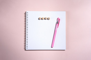 Opened book and pen on it on the pink background.