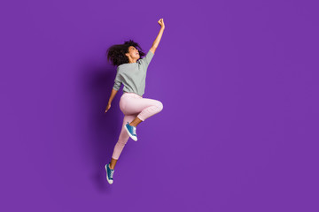 Full length photo of crazy funny afro american girl jump hold hand try catch parasol wear casual style pink outfit isolated over purple color background © deagreez