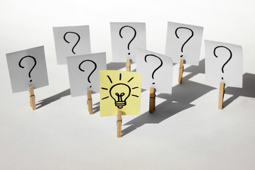 A lot of clothespins with question marks on stickers and on one light bulb, as a sign of a good idea.