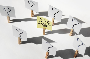 A lot of clothespins with question marks on stickers and on one light bulb, as a sign of a good idea.